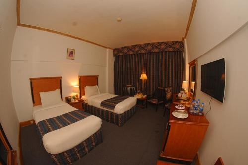 a hotel room with two beds and a television at Mehran Hotel Karachi in Karachi