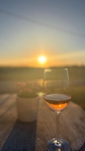 a glass of wine sitting on a table with the sunset at B&B Les Trois Pignons in Diksmuide