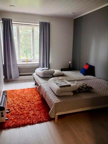 two beds in a bedroom with a red rug at Aliupseerikerho in Kauhava