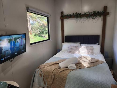 a bedroom with a bed with a tv on the wall at Rosebank Tiny House in Healesville
