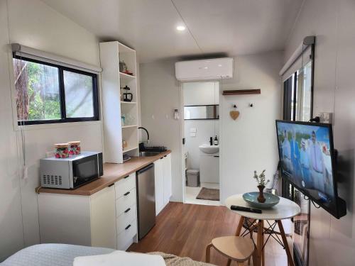 a small kitchen with a desk and a tv in a tiny house at Rosebank Tiny House in Healesville