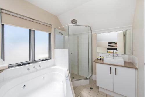 a white bathroom with a tub and a sink at Serenity Townhouse in Mandurah