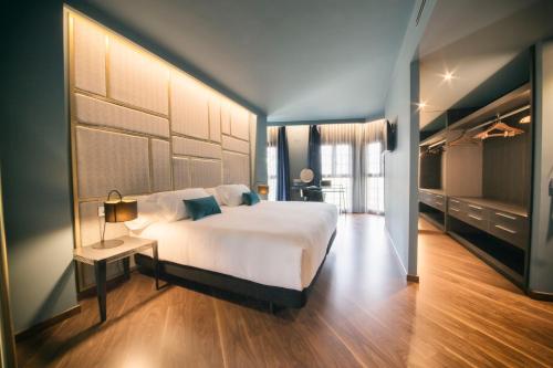1 dormitorio con 1 cama blanca grande, mesa y TV en Pamplona Catedral Hotel, en Pamplona