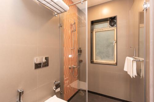 a bathroom with a shower and a toilet and a window at Ginger Katra in Katra