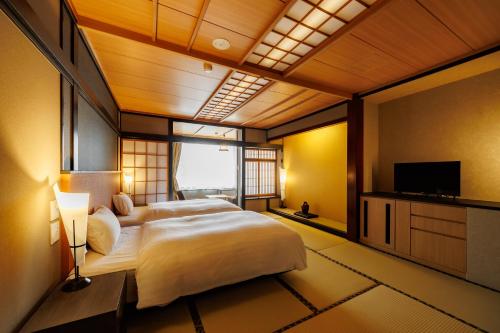 a bedroom with two beds and a flat screen tv at ホテルグランリゾート蓼科 in Chino