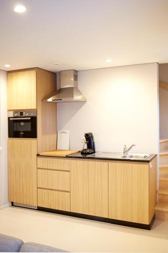 a kitchen with wooden cabinets and a sink at B2B-flats AALST in Aalst