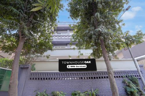 a sign in front of a building with trees at Townhouse Oak Sector 31 Noida in Noida