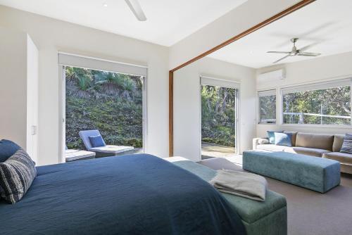 a bedroom with a blue bed and a couch at Timbara Hideaway - Ocean Views - Pet Friendly in Moggs Creek