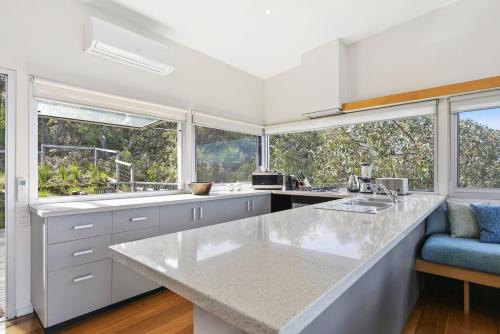 a kitchen with a large white counter top and windows at Timbara Hideaway - Ocean Views - Pet Friendly in Moggs Creek