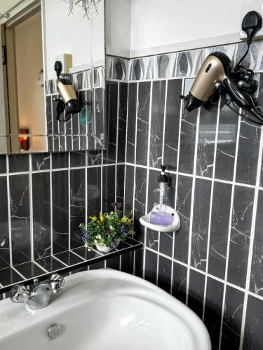 a black tiled bathroom with a sink and a mirror at Villa Sarakkuwa in Pamunugama
