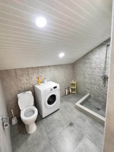 a bathroom with a toilet and a washing machine at Chkalovka Guest House With Sevan View in Sevan