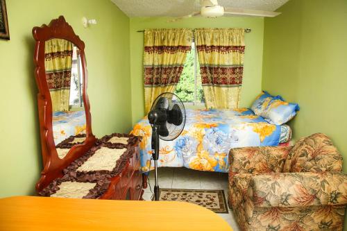 a bedroom with a bed and a mirror and a chair at Angel's Apartment Jamaica in Kingston