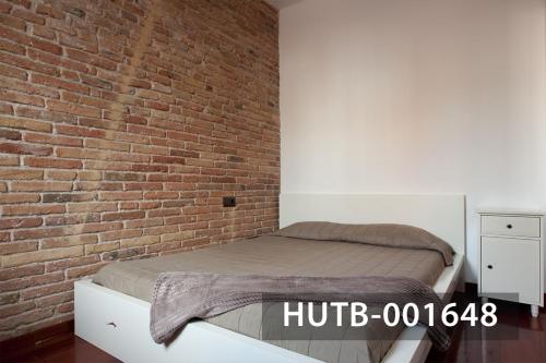a bed in a room with a brick wall at Ghat Apartment Poble Sec Barcelona in Barcelona