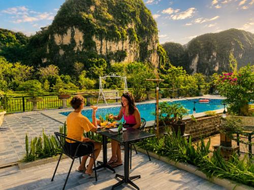 a man and woman sitting at a table in front of a pool at Tam Cốc AppA House in Ninh Binh