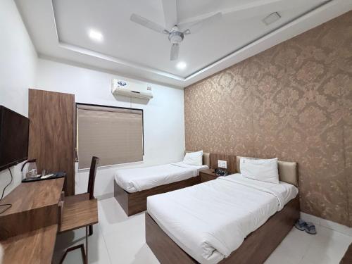 a room with two beds and a desk and a tv at Hotel SR Executive, Akola in Akola
