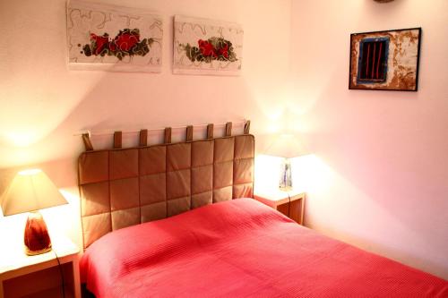 een slaapkamer met een bed met rode lakens en 2 lampen bij Chambre d'Hôtes la Poterie in Caunes-Minervois