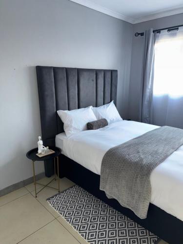 a bedroom with a large bed with a black headboard at Cubes Ledig Luxury Apartments in Ledig