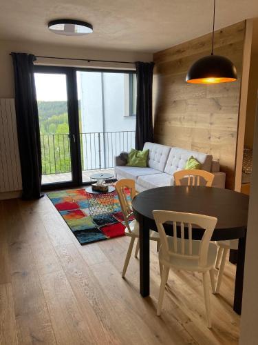 a living room with a table and a couch at Apartmán Brčálník Šumavské Stráně in Hojsova Stráž