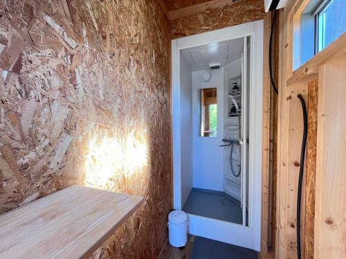 a tiny house with a stone wall and a shower at 里山グランピングむすび in Mizunami