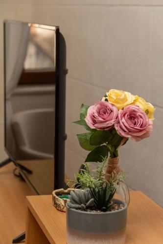 a vase filled with pink and yellow roses on a table at Step to Kotor Bay Old Town in Kotor