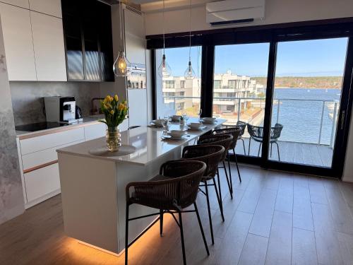 a kitchen with a long table with chairs and a large window at Aqua Concept Apartment Sol Marina in Wiślinka