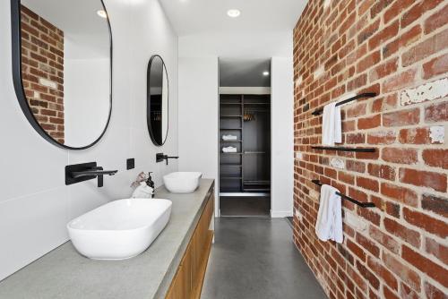 a bathroom with two sinks and a brick wall at Wild Wombat in Mansfield