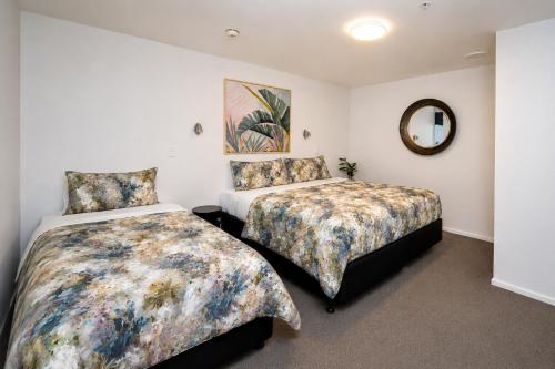 a bedroom with two beds and a mirror at Cathedral Junction Apartments in Christchurch