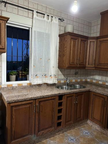 a kitchen with wooden cabinets and a sink and a window at Casa Manila in Colmenar