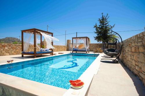 a swimming pool with two chairs next to a wall at Traounou Serenity Villa Near to Afandou Beach in Afantou