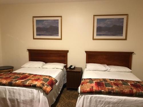 a hotel room with two beds and two pictures on the wall at Waterbury Big Apple Motel in Waterbury