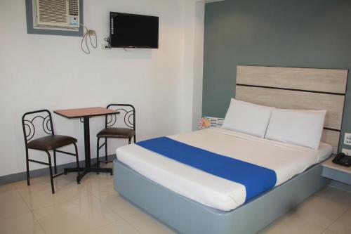 a bedroom with a bed and a table and a desk at Nice Hotel Aurora Cubao in Manila