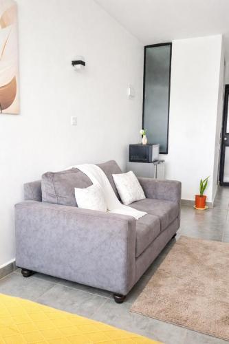 a living room with a gray couch in a room at Hise Haven Stays in Kiambu