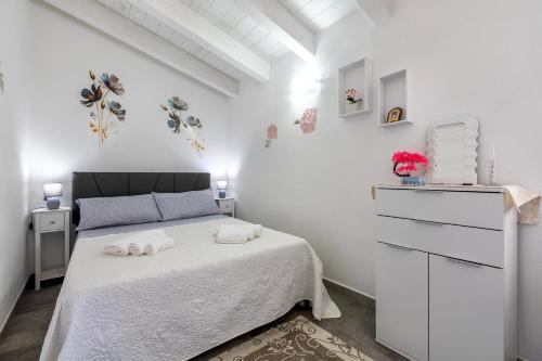 a white bedroom with a bed and a dresser at Villa Angela in Nulvi
