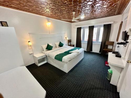 a hotel room with a bed with green sheets at Hotel Hamza in Srinagar