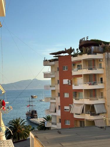 a tall building next to the water with a boat at Central Boutique Hostel in Sarandë