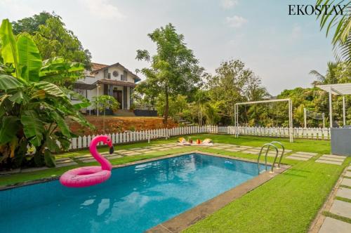 a swimming pool with a pink flamingo in a yard at EKOSTAY - Mount Emerald Villa in Alibaug