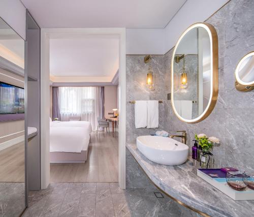 a bathroom with a sink and a bed and a mirror at Mercure Shenzhen Nanshan in Shenzhen