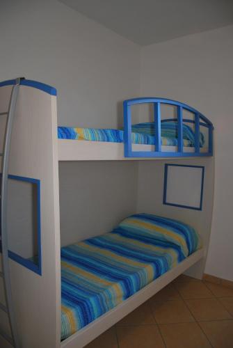 two bunk beds in a white room with a striped mattress at Appartamenti Margherita - Zona mare con clima e posti auto in Campo nell'Elba
