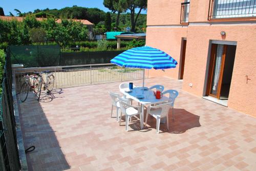 a table and chairs with an umbrella on a patio at Appartamenti Margherita - Zona mare con clima e posti auto in Campo nell'Elba