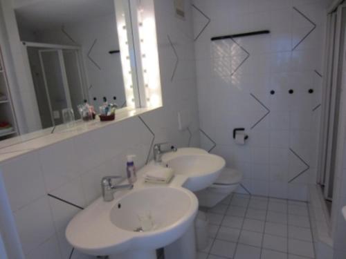 a white bathroom with two sinks and a toilet at Residenz al Parco in Ascona