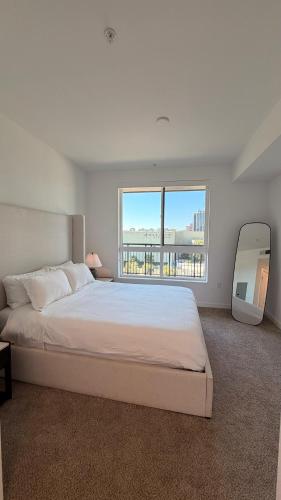 a white bedroom with a large bed and a large window at Wallace Luxurious in Los Angeles