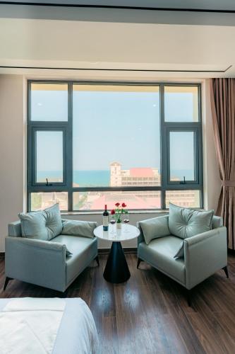 a living room with two couches and a table and windows at Long Hotel in Danang
