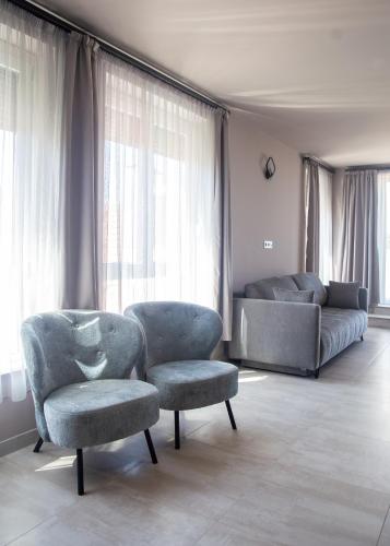a living room with two chairs and a couch at Maya Panzio-Rezidencia in Szeged