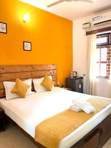 a bedroom with a large bed with yellow walls at Fatima Guest House in Baga