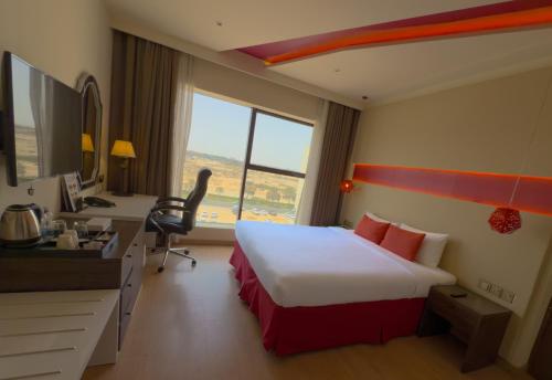 a hotel room with a bed and a desk and a computer at Carnelian Muscat - Airport Hotel in Muscat