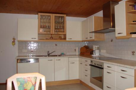 a kitchen with white cabinets and a chair in it at Ferienwohnung Nussbaum in Stummerberg