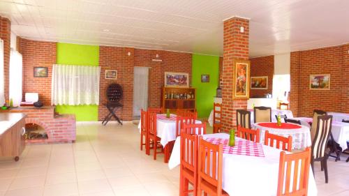 a restaurant with tables and chairs and green walls at Pousada Ponta da Pedra in Pedra Azul