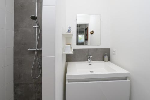 a white bathroom with a sink and a shower at Chambre d'hôtes Spiren in Baden