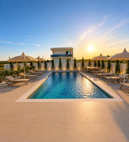 a resort swimming pool with tables and umbrellas at Villa Azur in Draç