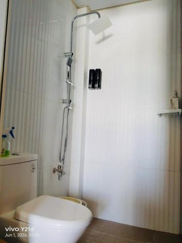 a white bathroom with a shower and a toilet at Rustic Retreat Three Bedroom House in Pagdalagan